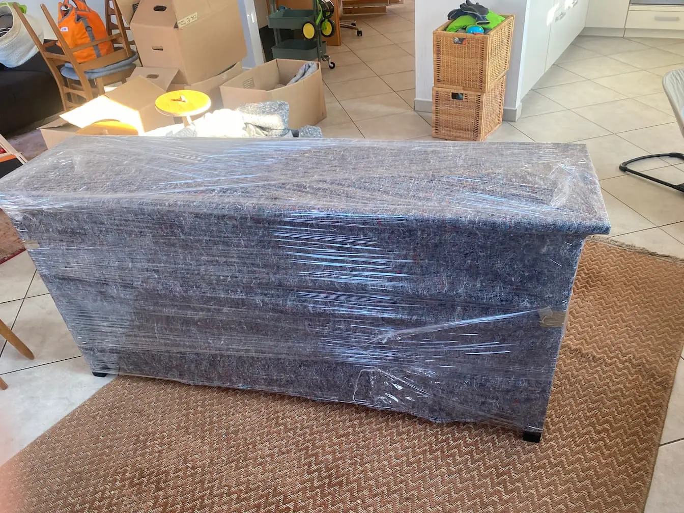 Ein Sideboard, in eine Möbeldecke gehüllt und darüber mit Stretchfolie umwickelt